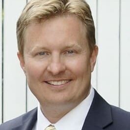 A man in suit and tie smiling for the camera.